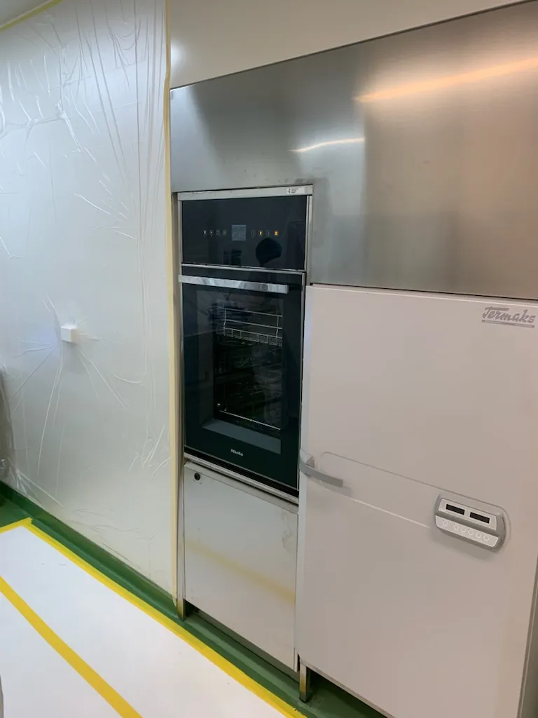 Miele-maskin under inbyggnad med byggplast och skyddstäckt golv omkring