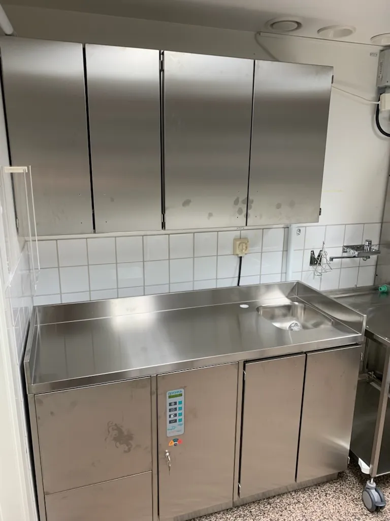 Rostfri arbetsbänk med ho och överskåp i rostfritt i ett spolrum