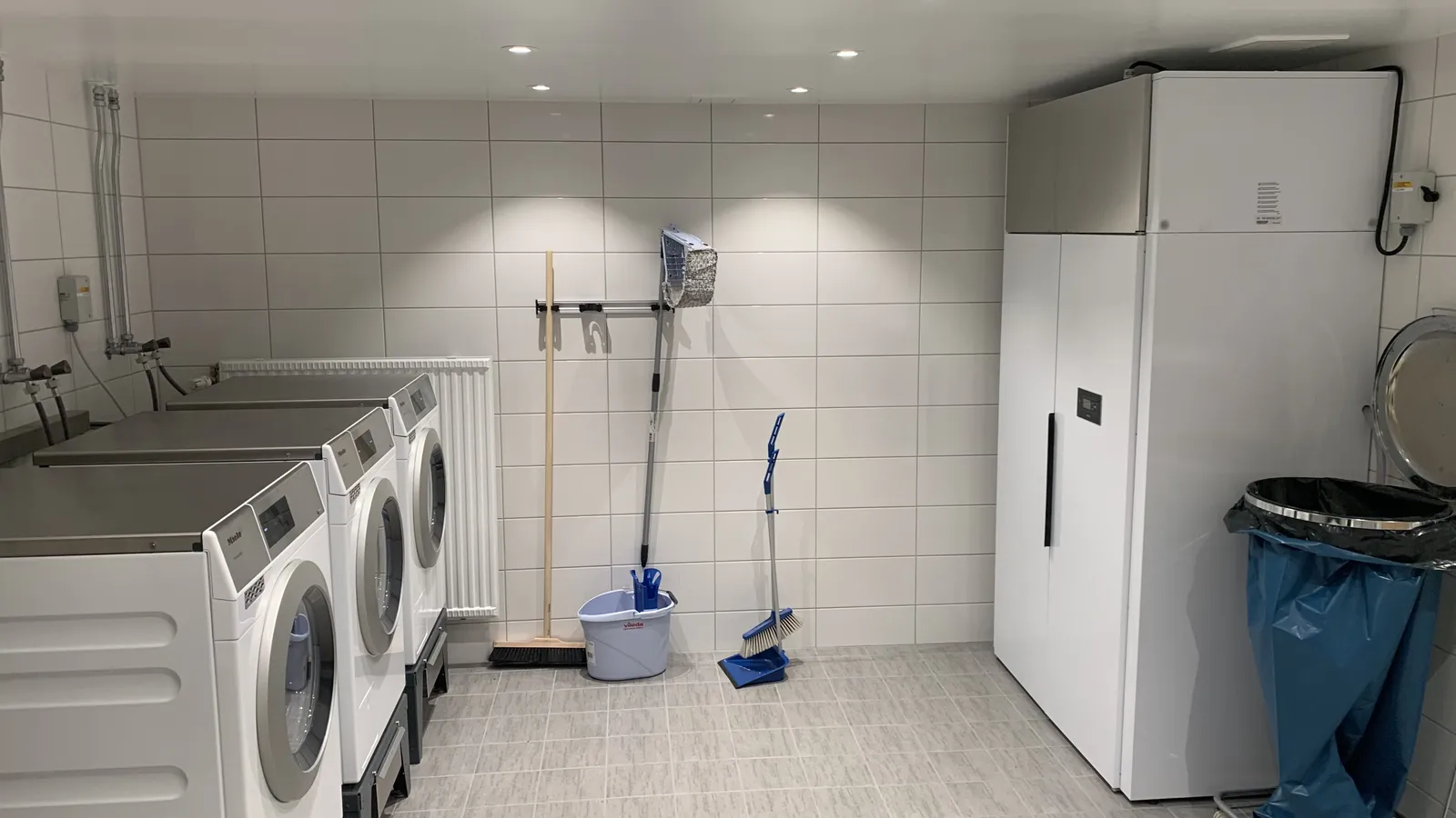 Färdigställd tvättstuga med tvättmaskiner, torkskåp och städutrustning på plats